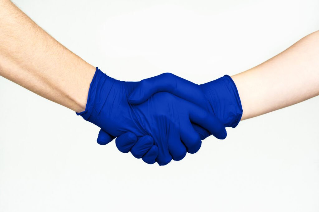 Two people shaking hands while wearing blue nitrile examination gloves
