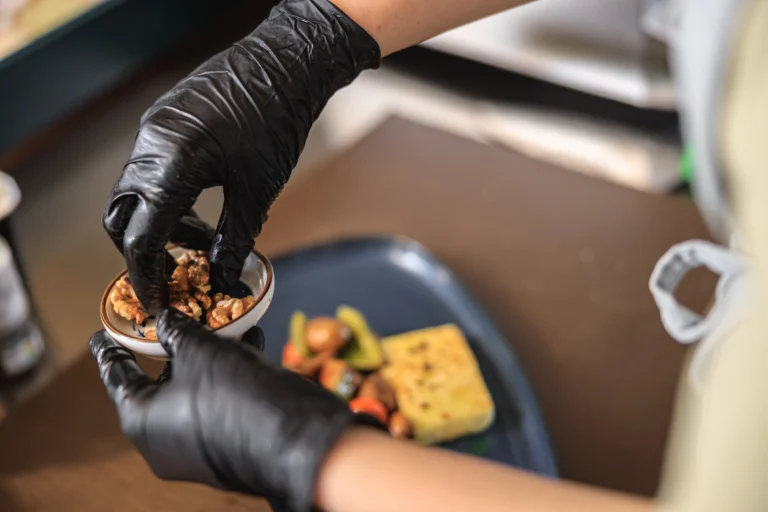kitchen worker wearing a black nitrile glove while preparing food